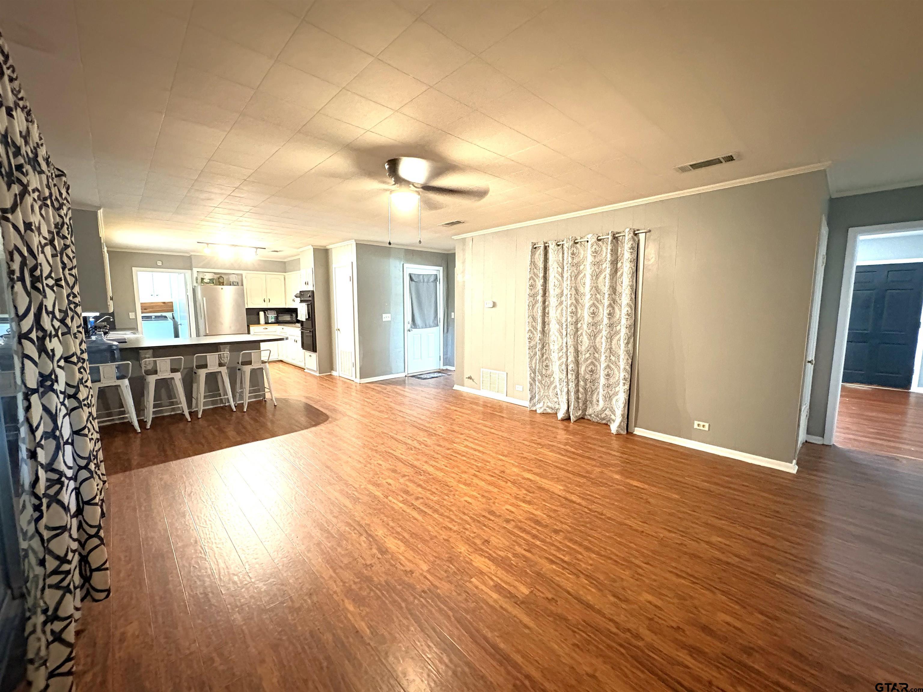 409 East Main Street Omaha, TX 75571 - Photo 2 of 15 a view of a living room a dining room with wooden floor and windows