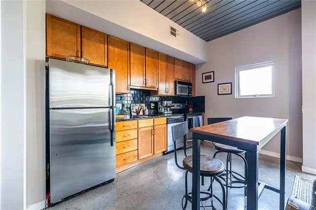 a kitchen with stainless steel appliances granite countertop a refrigerator and a stove top oven