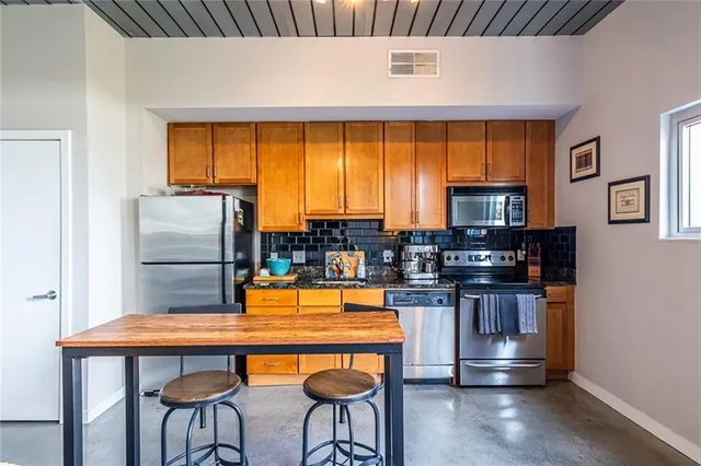 a kitchen with stainless steel appliances a table chairs and a refrigerator