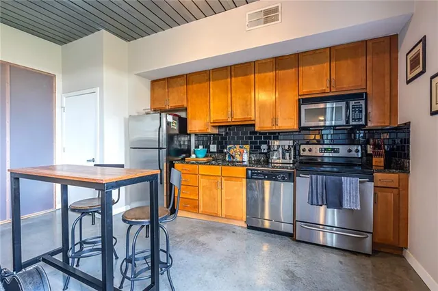 a kitchen with stainless steel appliances granite countertop a stove a sink dishwasher and a refrigerator