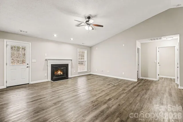 an empty room with wooden floor fireplace and fan