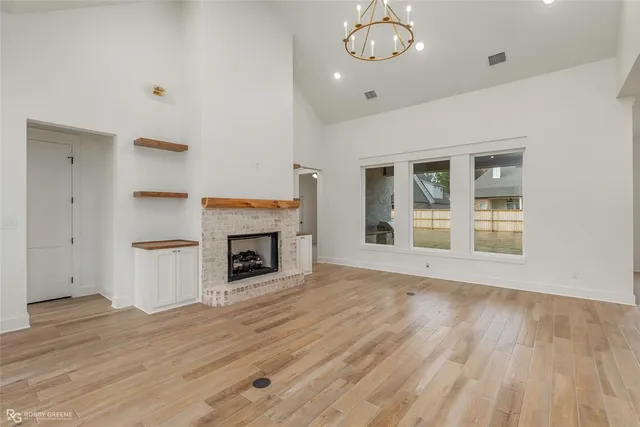 an empty room with wooden floor fireplace and windows