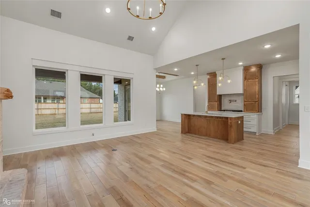 a view of an empty room with wooden floor and a kitchen