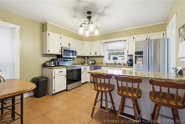 a kitchen with stainless steel appliances granite countertop a stove a sink dishwasher a dining table and chairs with wooden floor