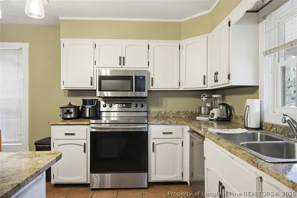 a kitchen with granite countertop white cabinets and a stove top oven
