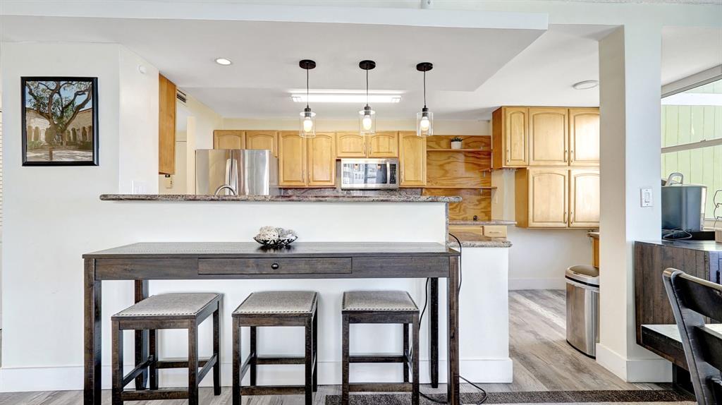 4400 Hillcrest Drive, Unit 719C Hollywood, FL 33021 - Photo 4 of 39 a kitchen with granite countertop a table chairs microwave and cabinets