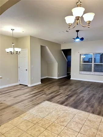 a view of a room with a chandelier fan and wooden floor