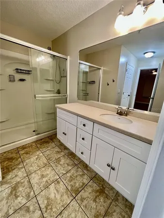 a spacious bathroom with a granite countertop sink a mirror and shower
