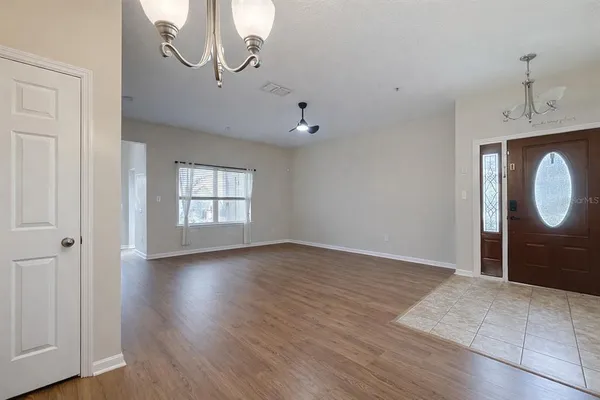 a view of an empty room with wooden floor and window