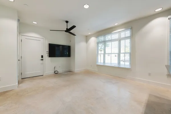 an empty room with windows and a ceiling fan