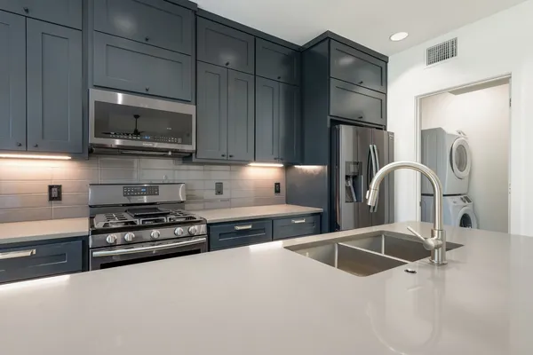 a kitchen with stainless steel appliances a sink a stove a microwave a sink a refrigerator and cabinets