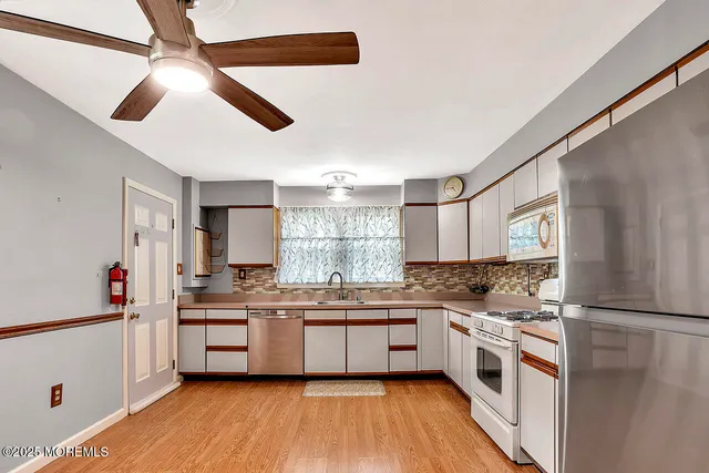 a kitchen with stainless steel appliances a sink cabinets and wooden floor