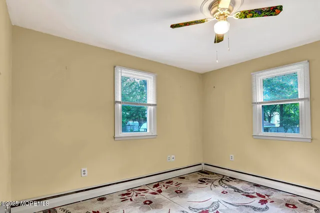 a view of an empty room with window and wooden floor
