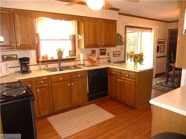 2254 Cullen Road Gibsonville, NC 27249 - Photo 5 of 16 Kitchen. Oak cabinets, stainless steel sink, dishwasher, electric range/oven, refrigerator, bar with stools, hardwood floors