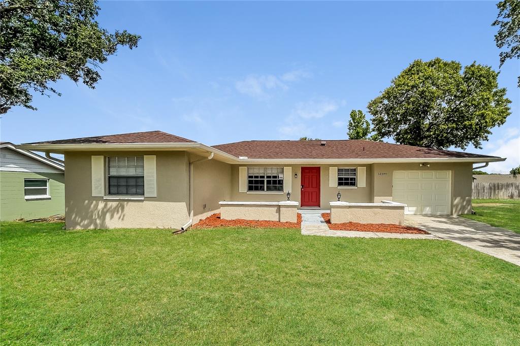 12345 Mayberry Road Spring Hill, FL 34609 - Photo 1 of 16 a front view of a house with a garden and trees