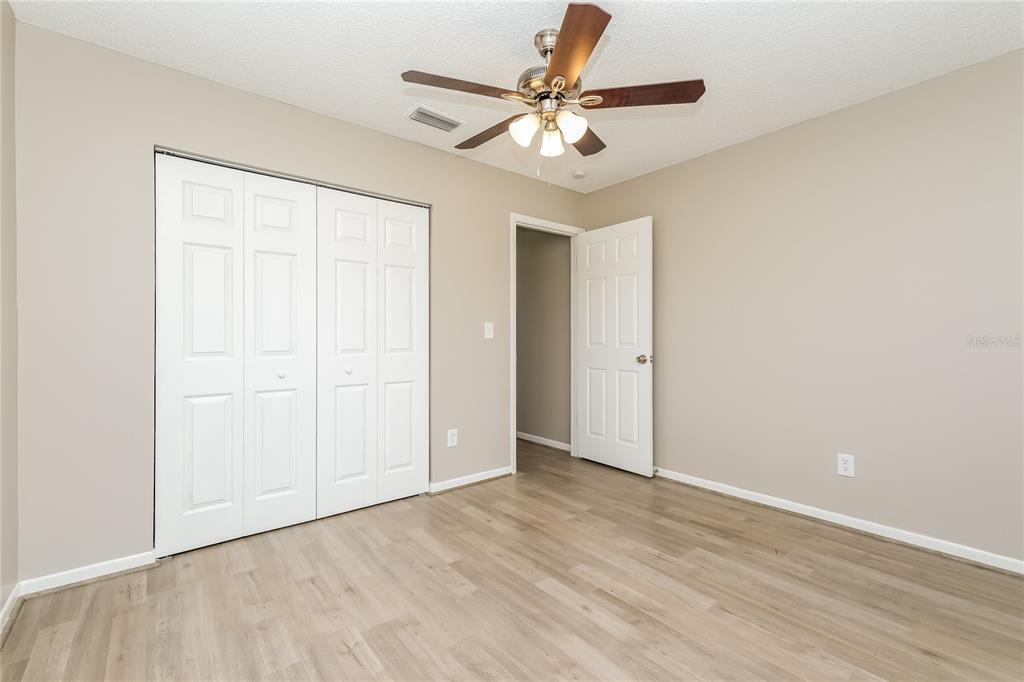 12345 Mayberry Road Spring Hill, FL 34609 - Photo 13 of 16 an empty room with a ceiling fan and wooden floor