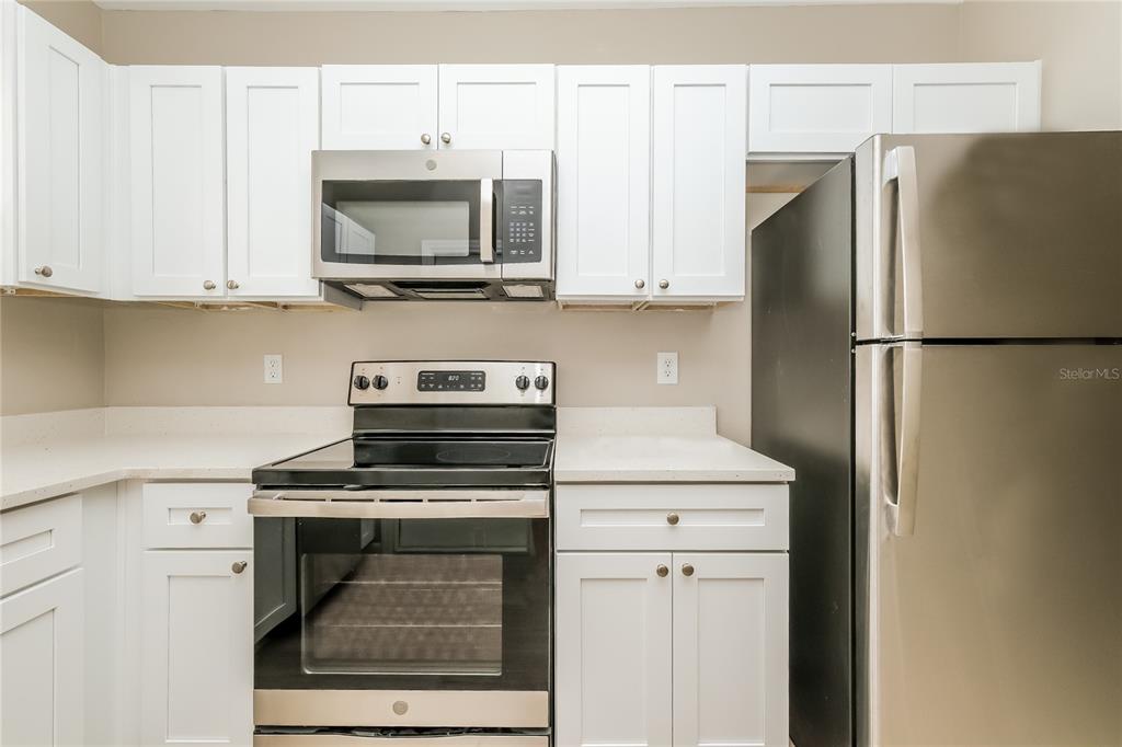 12345 Mayberry Road Spring Hill, FL 34609 - Photo 6 of 16 a kitchen with stainless steel appliances white cabinets and a refrigerator