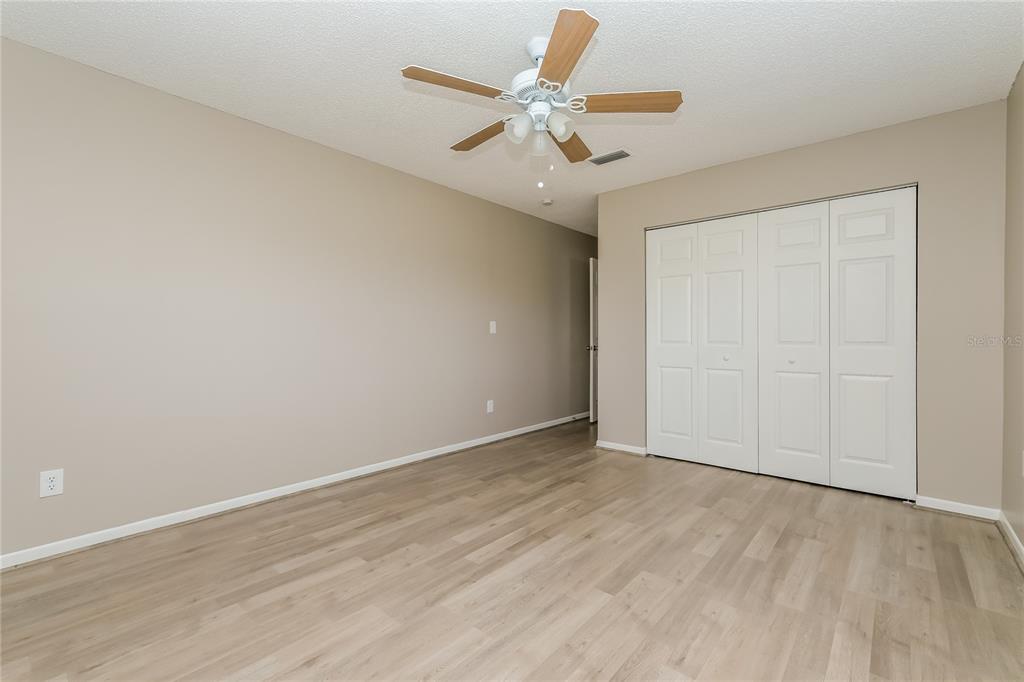 12345 Mayberry Road Spring Hill, FL 34609 - Photo 9 of 16 an empty room with a ceiling fan and wooden floor