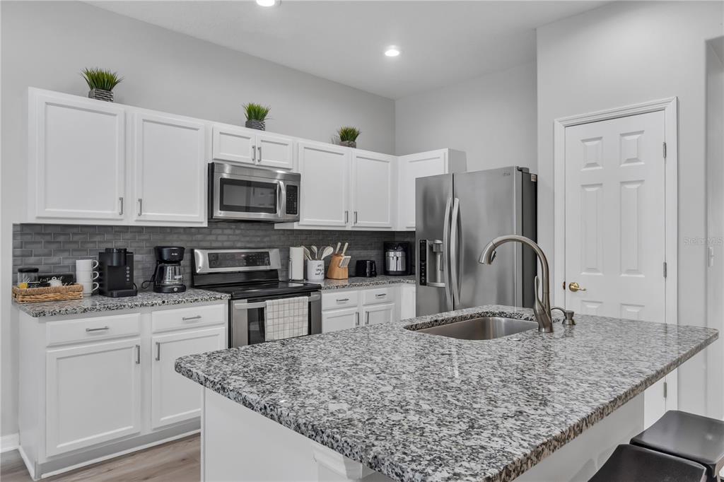 506 Kettering Road Davenport, FL 33897 - Photo 9 of 45 a kitchen with stainless steel appliances granite countertop a sink stove and refrigerator