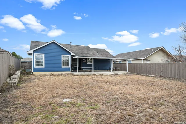a view of a house with a yard and wooden fence