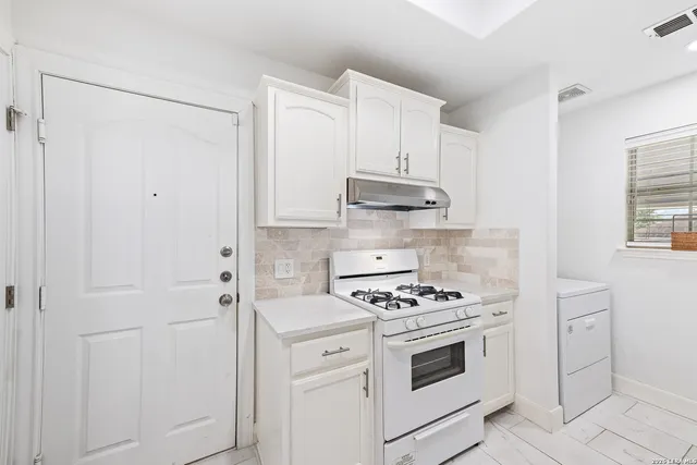 a kitchen with white cabinets and appliances