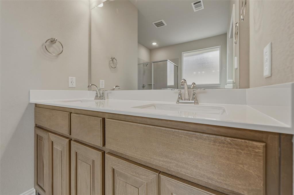 1201 Colca Drive Springtown, TX 76082 - Photo 24 of 32 Dual undermount sinks with brushed nickel fixtures, set in a light-colored countertop over wood-finish cabinetry