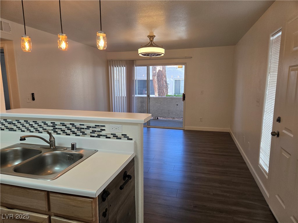 3168 Tarpon, Unit 103 Las Vegas, NV 89120 - Photo 2 of 23 Kitchen featuring light countertops, hanging light fixtures, dark wood-type flooring, and decorative backsplash