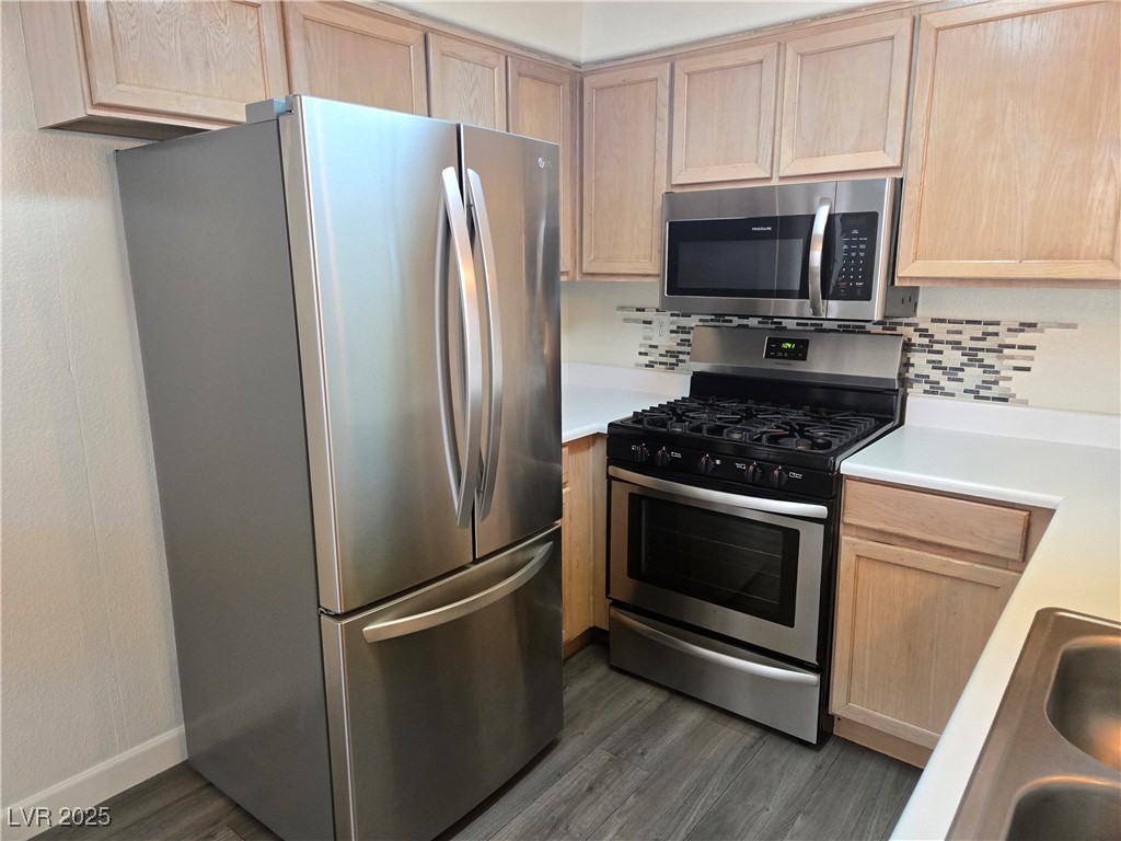 3168 Tarpon, Unit 103 Las Vegas, NV 89120 - Photo 3 of 23 Kitchen featuring appliances with stainless steel finishes, light countertops, light brown cabinetry, and tasteful backsplash