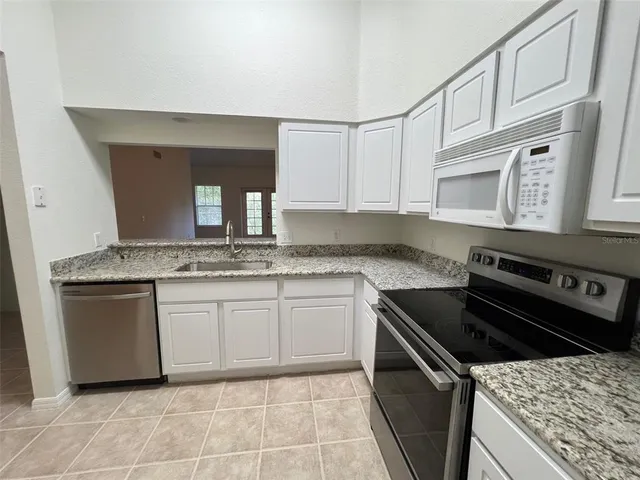 a kitchen with granite countertop a sink a stove and cabinets