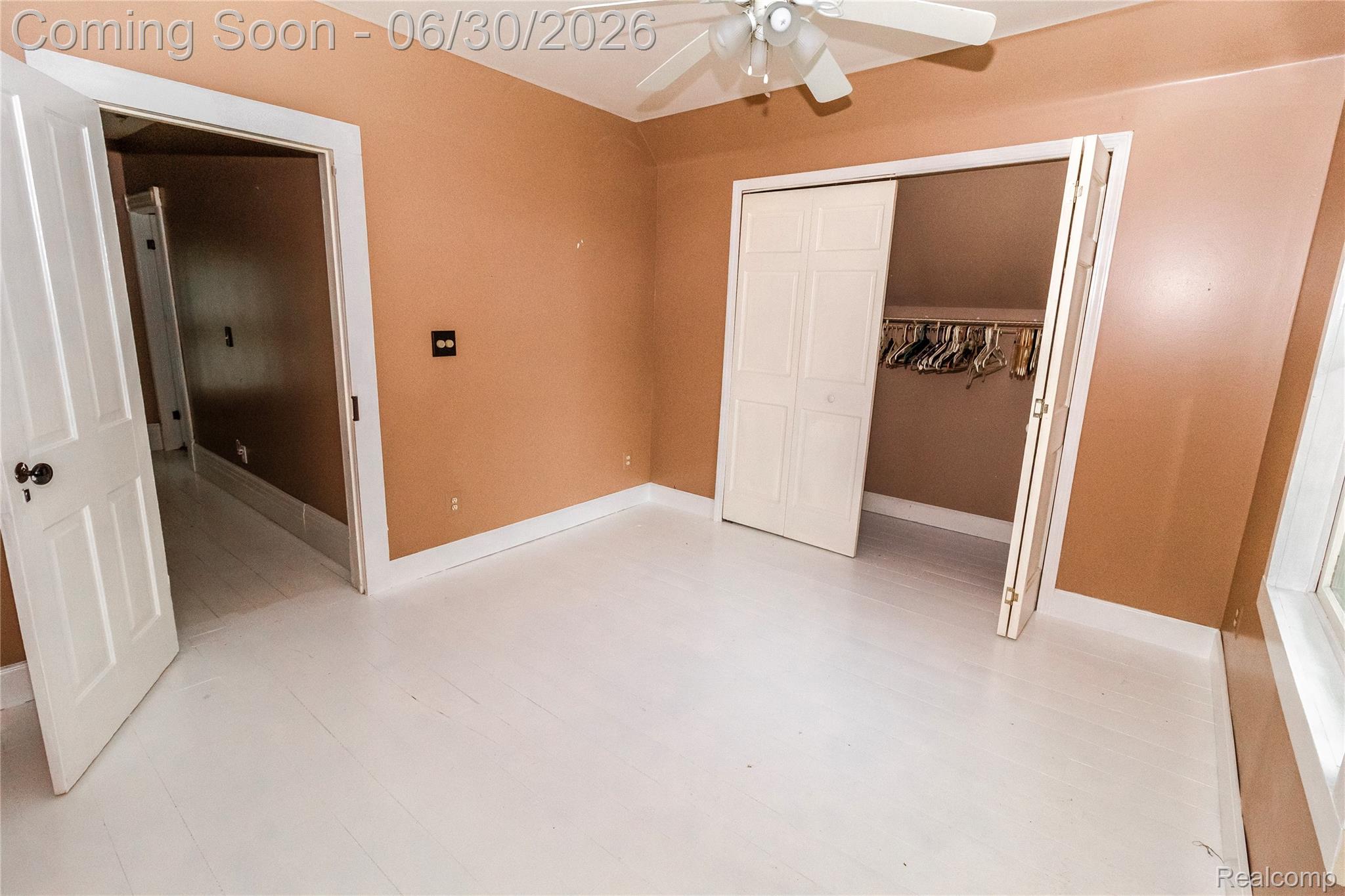 8150 Norman Road Imlay City, MI 48444 - Photo 33 of 58 Spacious room featuring white wood-finish flooring, warm-toned walls, a ceiling fan with light fixture, and a bi-fold door closet with hanging rod