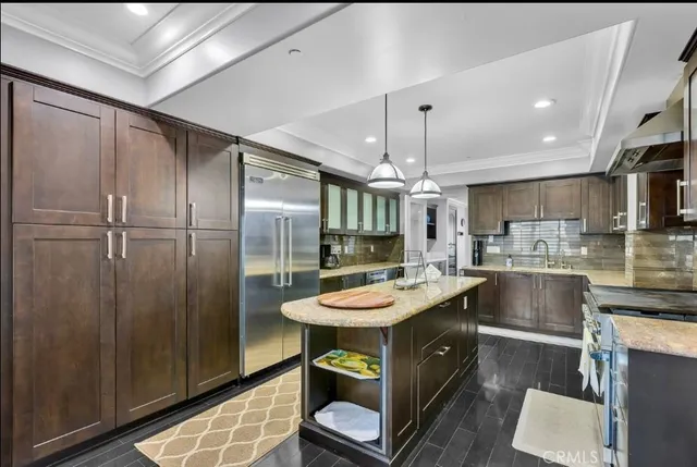a kitchen with granite countertop a refrigerator a stove a sink dishwasher a oven with white cabinets and countertops