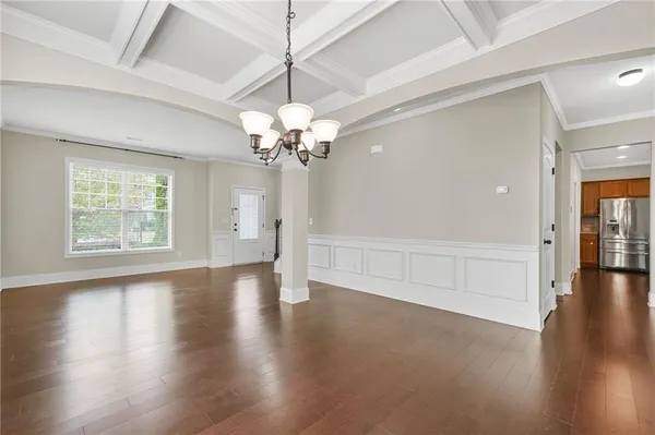 an empty room with wooden floor chandelier and windows