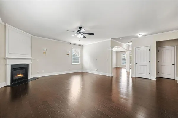 a view of an empty room with wooden floor and a fireplace