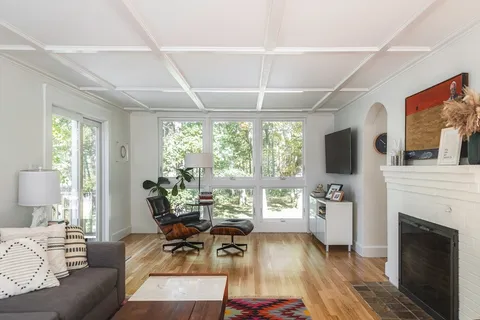 a living room with furniture a fireplace and a floor to ceiling window