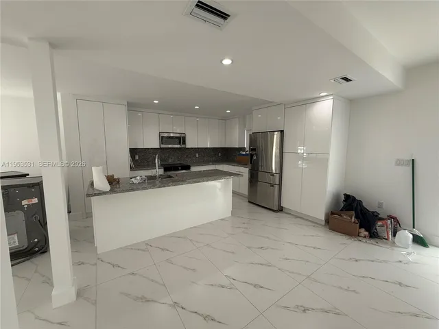 a large white kitchen with stainless steel appliances granite countertop a sink and a stove top oven