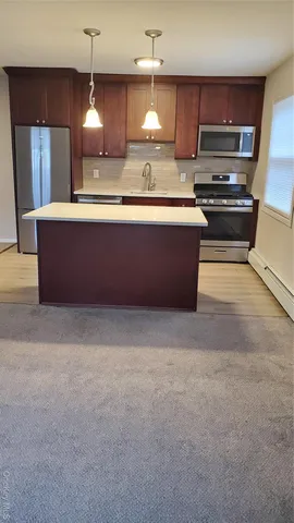 a kitchen with kitchen island granite countertop a sink counter top space cabinets and stainless steel appliances