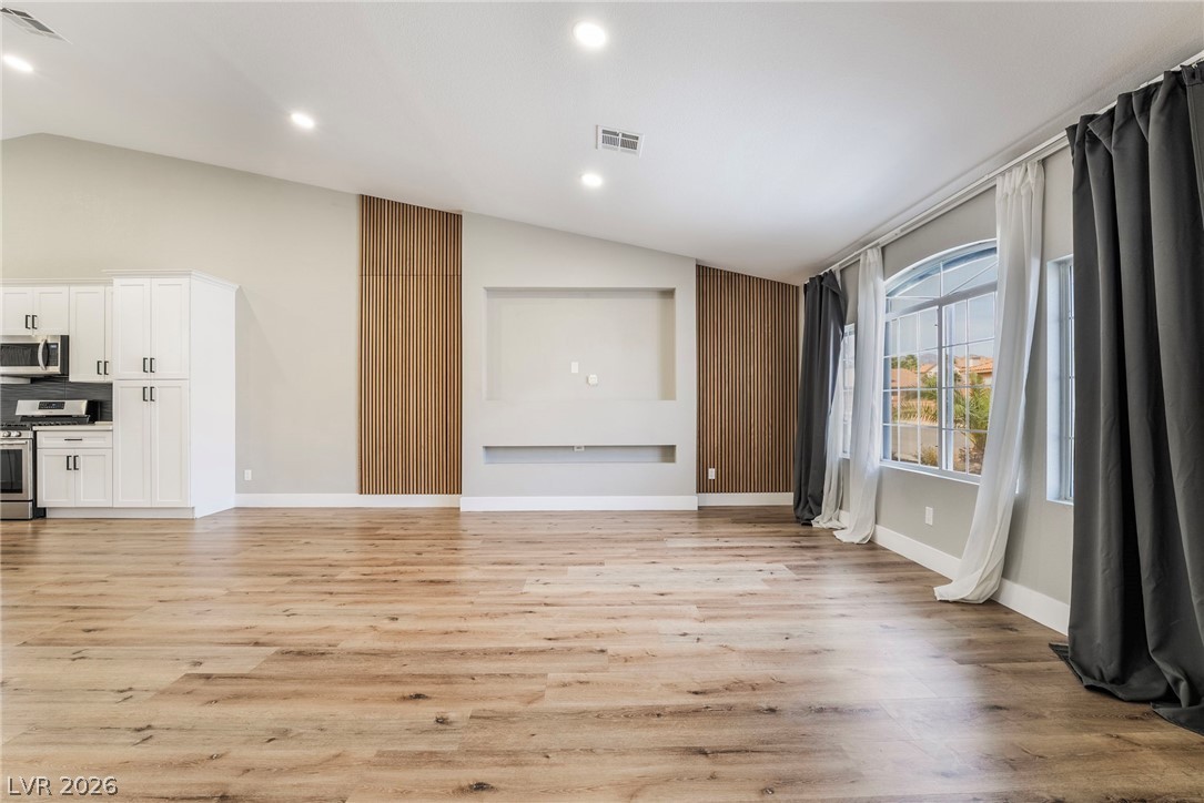 9171 West Viking Road Las Vegas, NV 89147 - Photo 8 of 43 Natural wood flooring complements the vaulted ceiling in this spacious, sunlit great room.