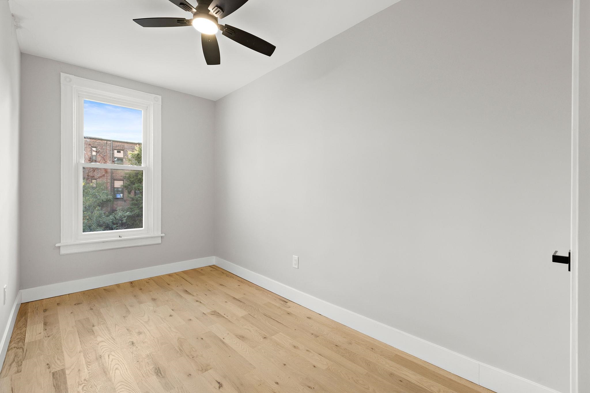 77 Boyd Avenue Jersey City, NJ 07304 - Photo 11 of 26 an empty room with a window and ceiling fan