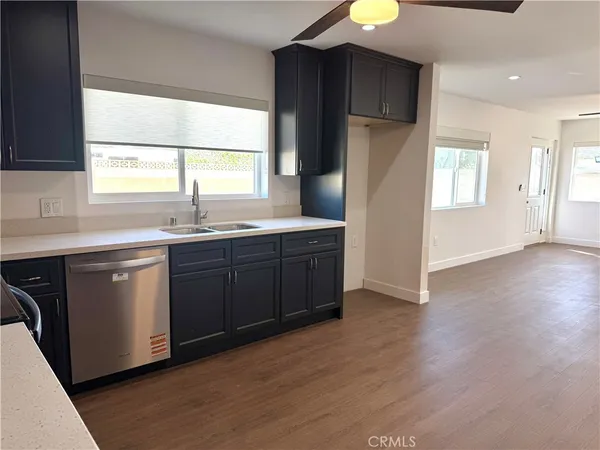 a kitchen with stainless steel appliances granite countertop a sink a refrigerator and wooden floor