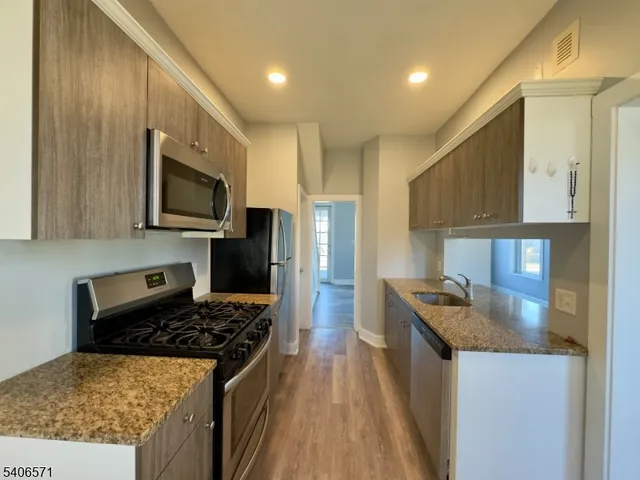 a kitchen with stainless steel appliances granite countertop a stove a sink a refrigerator and a microwave