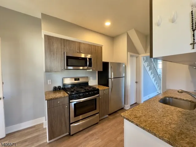 a kitchen with stainless steel appliances granite countertop a stove a sink and a refrigerator
