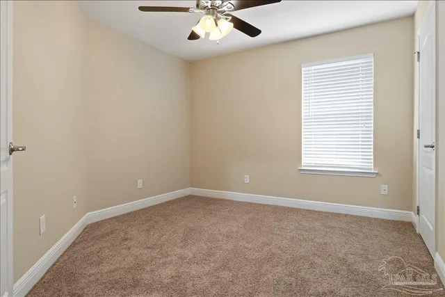 an empty room with a window and a ceiling fan