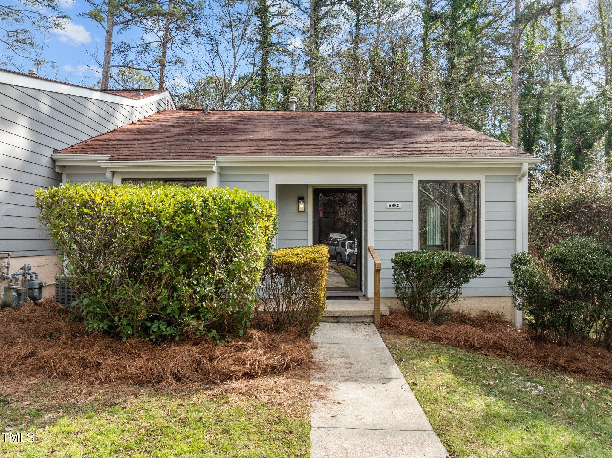 5850 Branchwood Road Raleigh, NC 27609 - Photo 1 of 27 a view of a house with brick walls plants and large tree