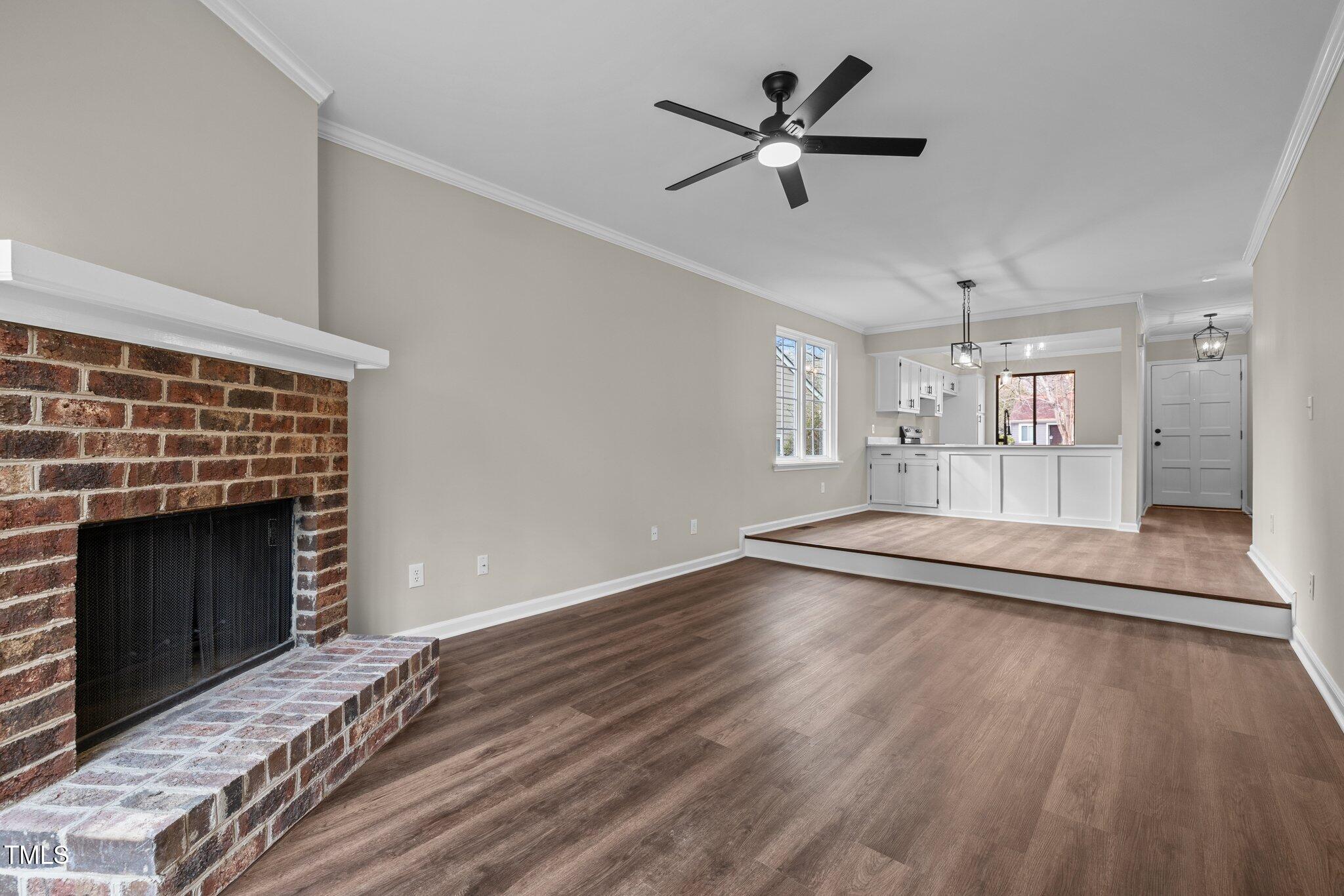 5850 Branchwood Road Raleigh, NC 27609 - Photo 12 of 27 a view of a livingroom with a fireplace a ceiling fan and wooden floor