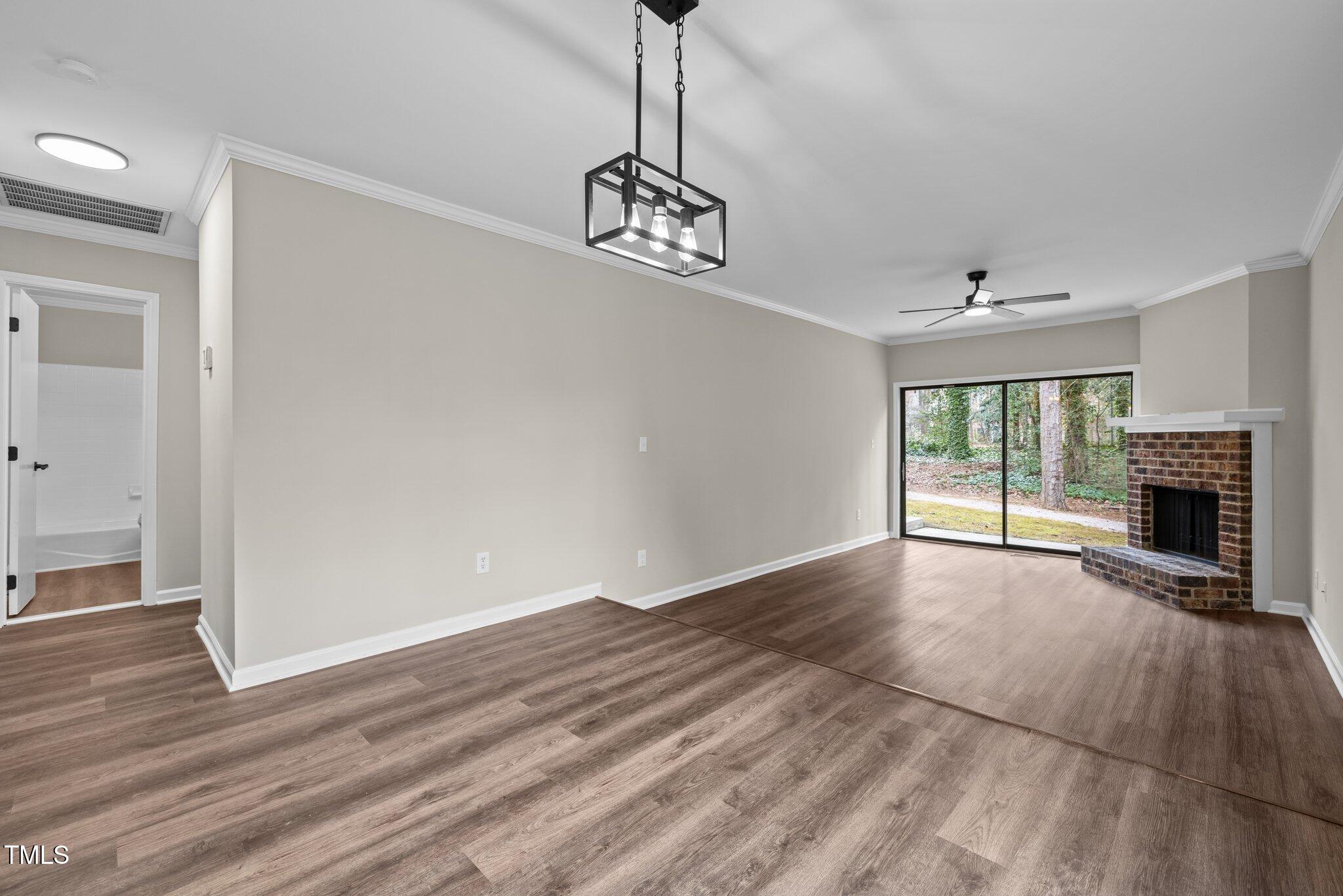 5850 Branchwood Road Raleigh, NC 27609 - Photo 7 of 27 a view of an empty room with wooden floor fireplace and a window