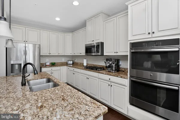 a kitchen with kitchen island a white counter top space cabinets and stainless steel appliances