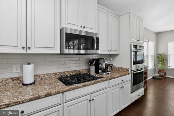 a kitchen with stainless steel appliances granite countertop a refrigerator and white cabinets