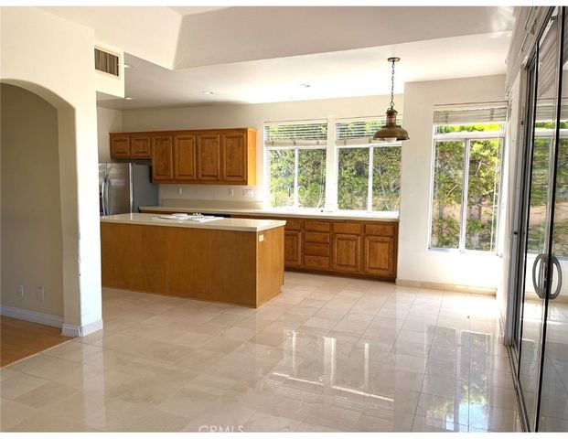 a large kitchen with kitchen island a large window a sink and stainless steel appliances