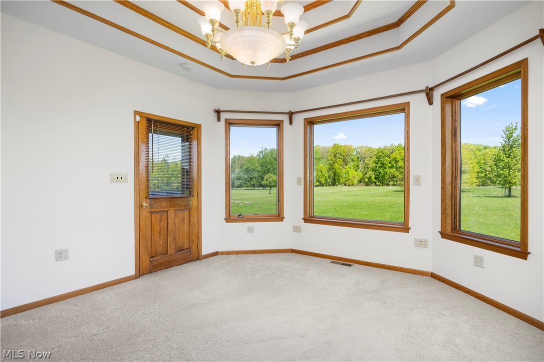 51488 Peck Wadsworth Road Wellington, OH 44090 - Photo 23 of 50 Room with light-colored carpet, a wood-finish door, and multiple large windows with wood-finish trim