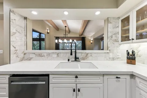 a large kitchen with stainless steel appliances granite countertop a stove top oven a sink dishwasher and white cabinets with wooden floor